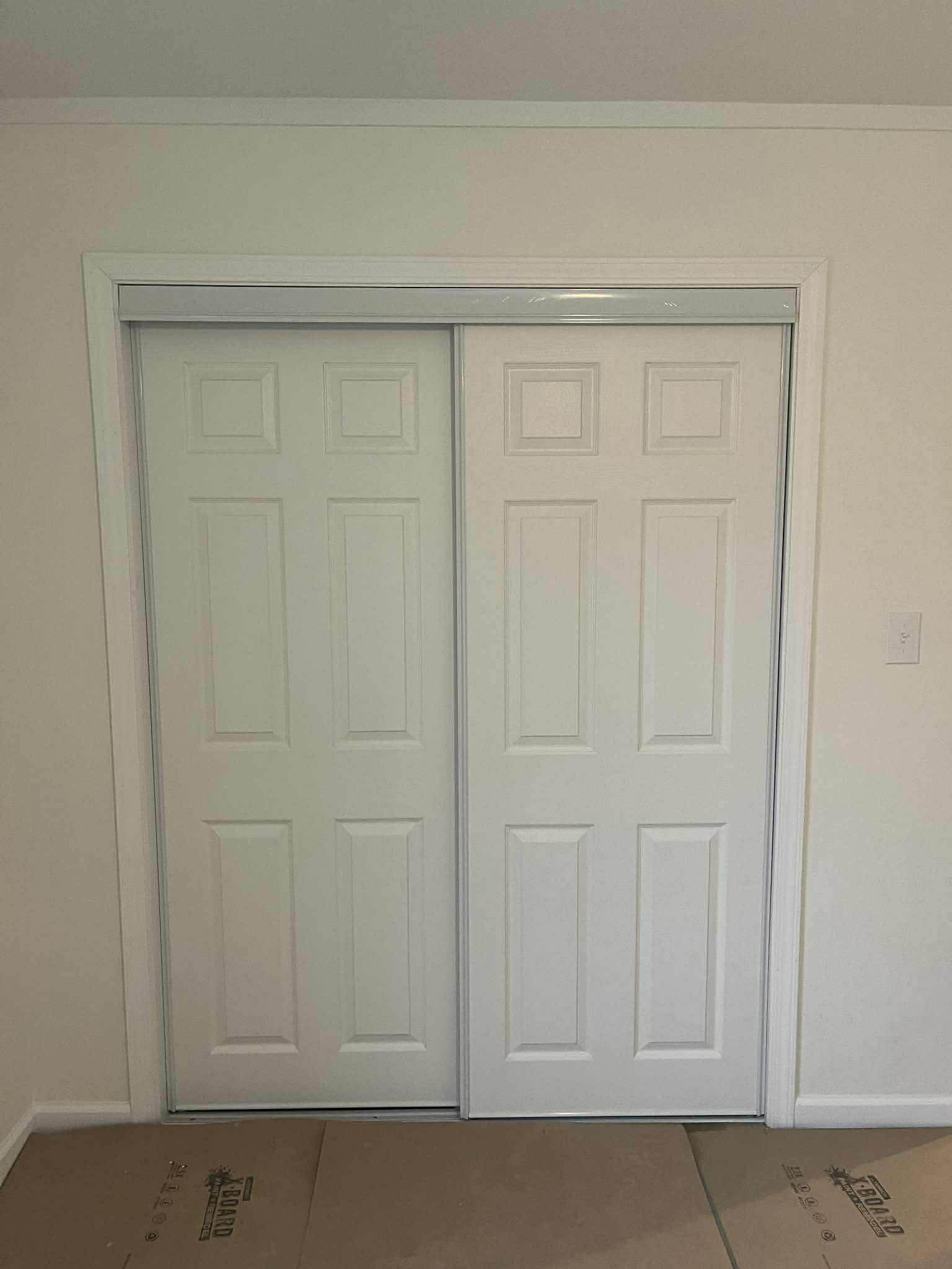 White six-panel sliding bypass closet doors with track installation