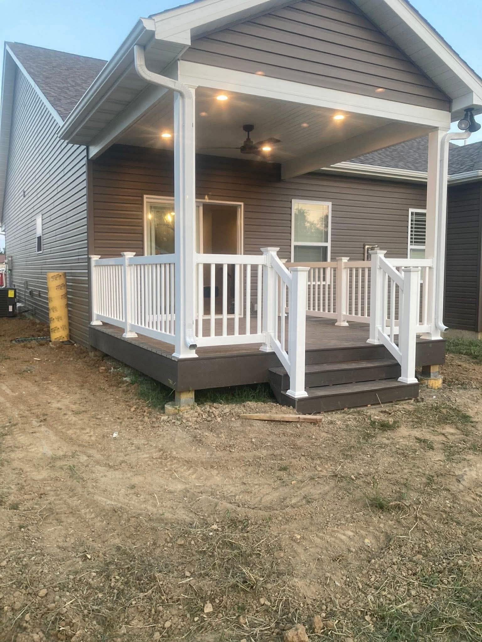 Covered composite deck with white vinyl railing and recessed lighting built by Frame to Finish