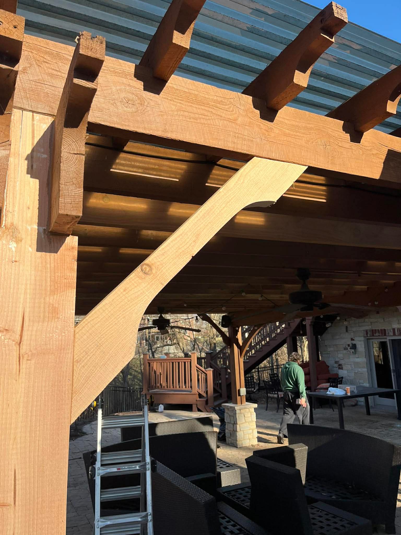 Custom cedar pergola with timber beam construction and corrugated metal roof for outdoor living area