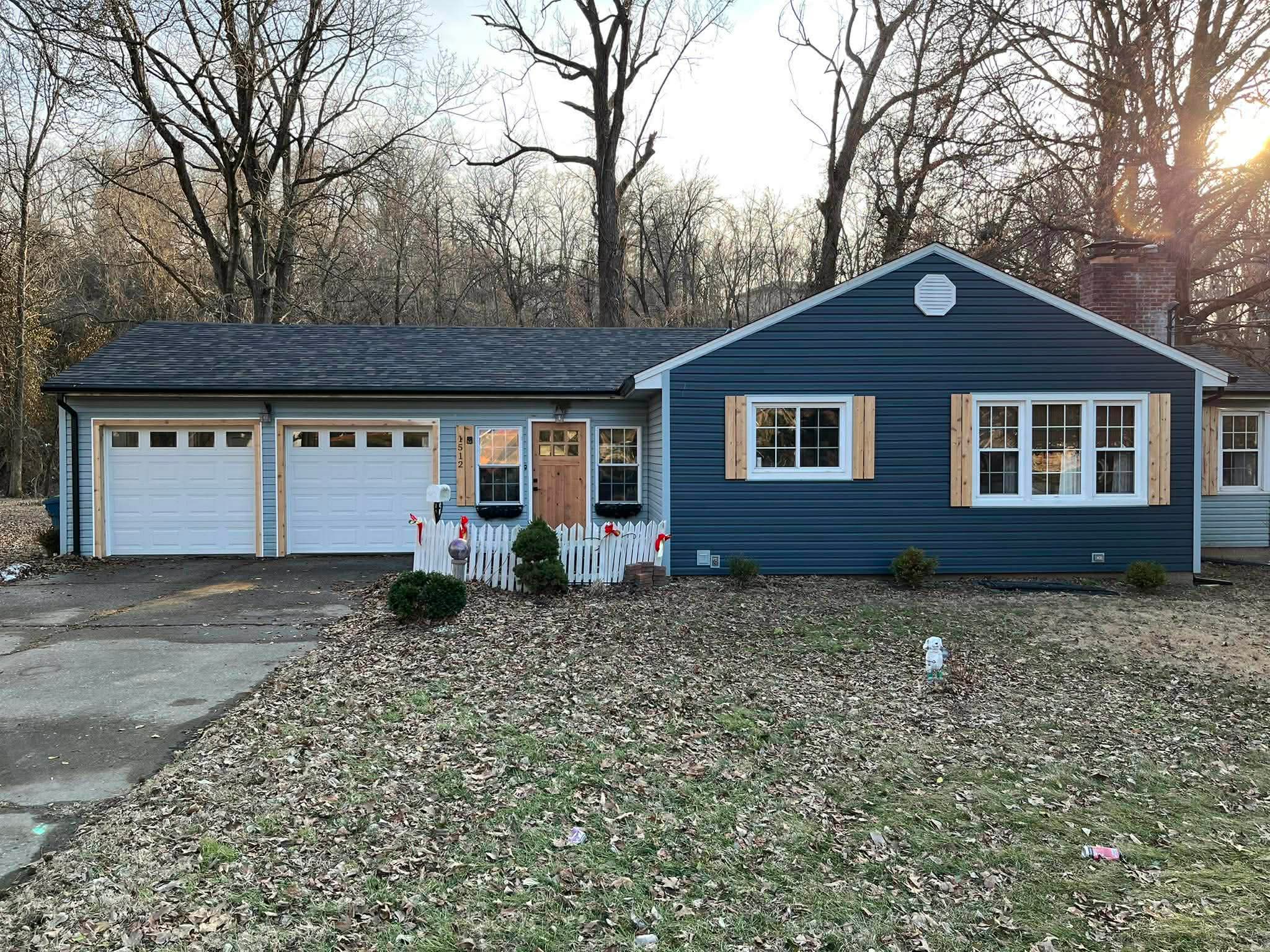 Complete home exterior renovation with blue siding, new garage doors, and craftsman entry door