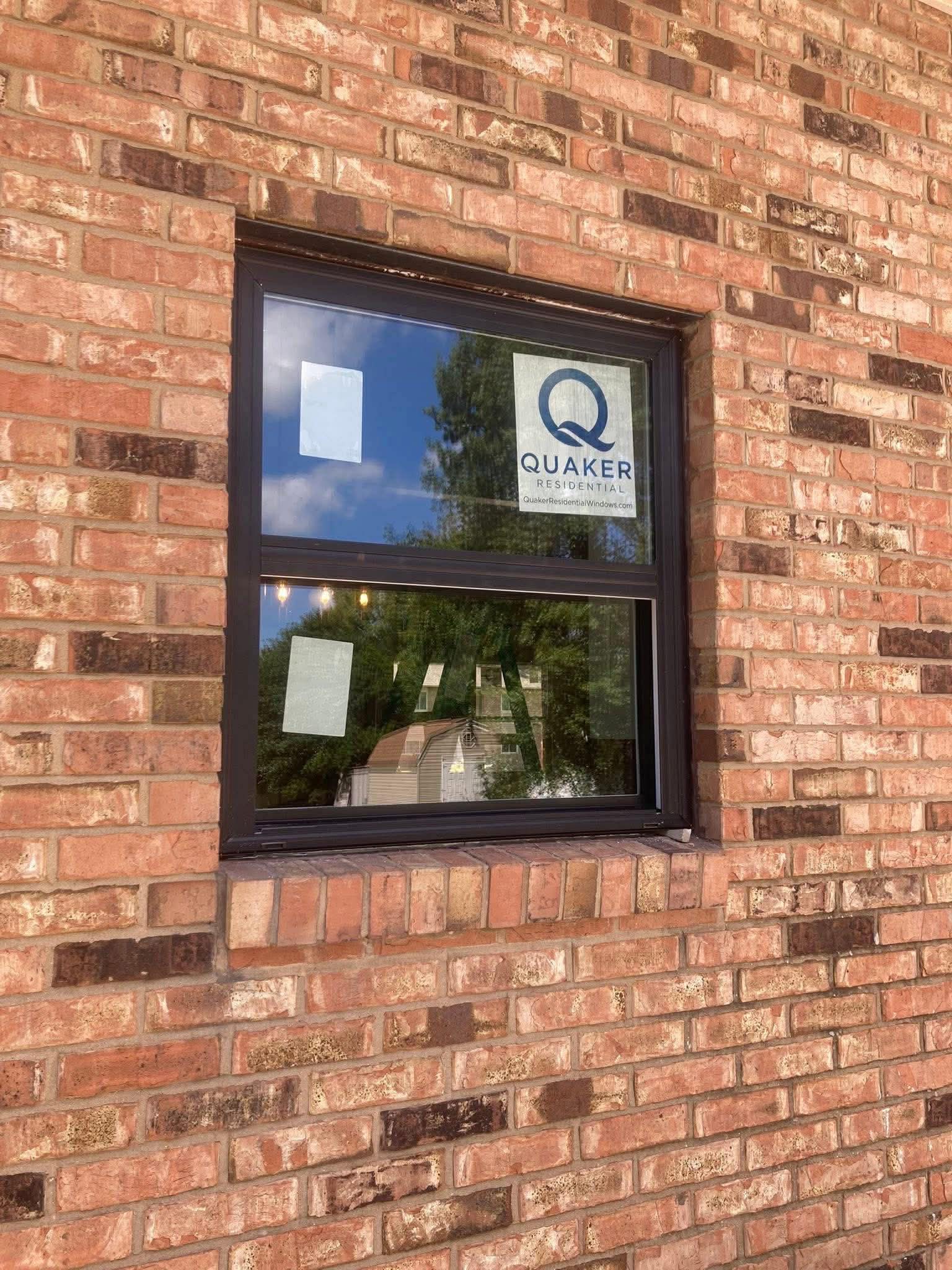 Quaker residential window installation on brick home exterior