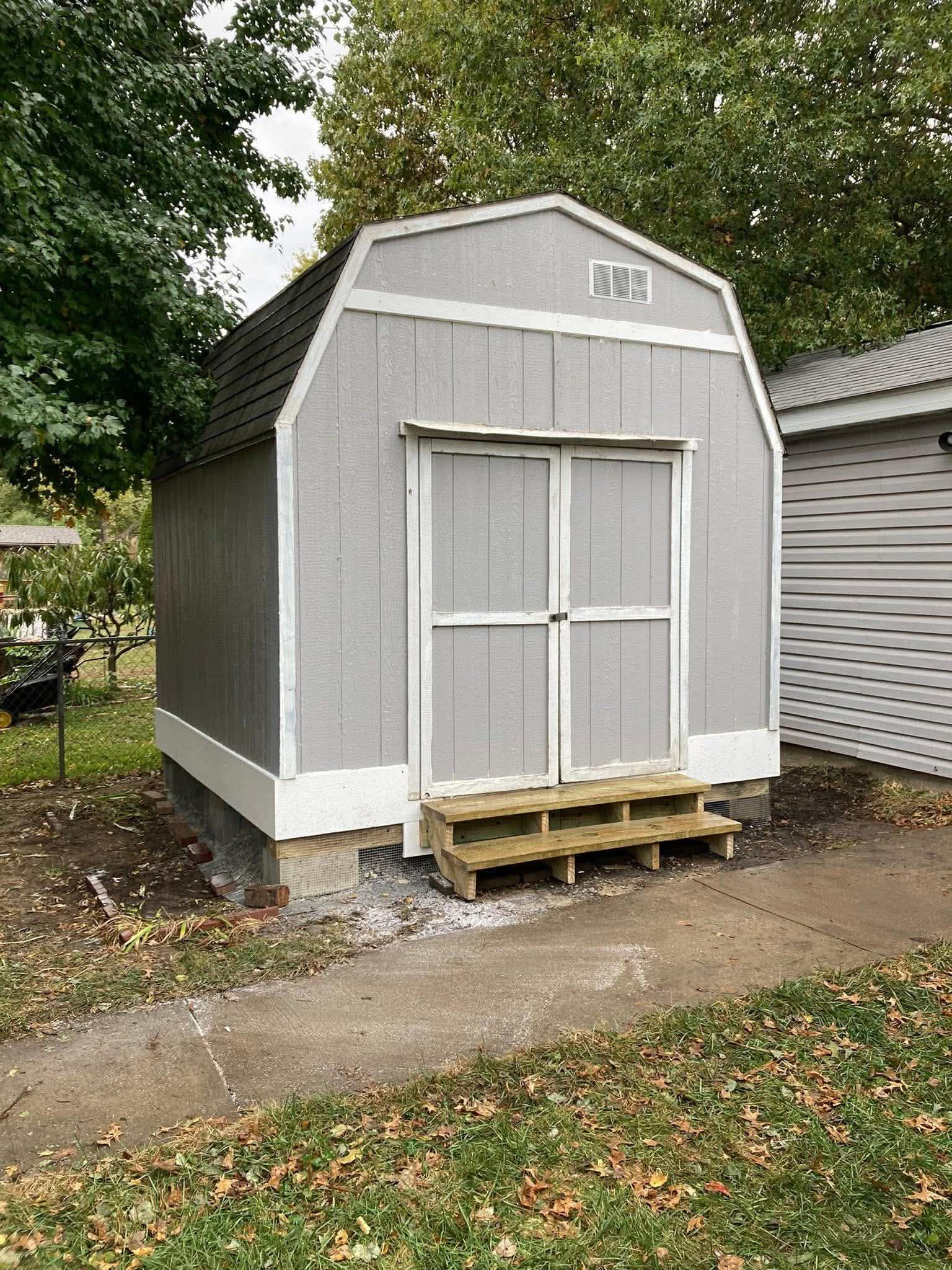 Custom storage shed build with gambrel roof and wooden entry steps