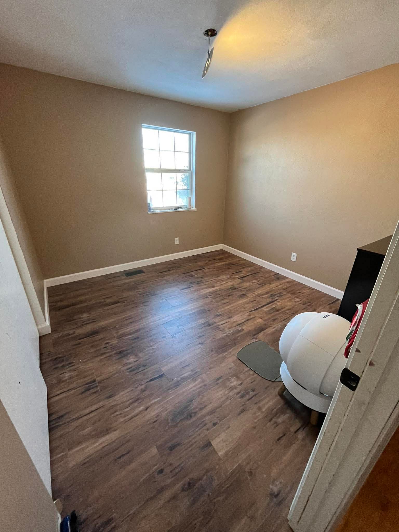 Vinyl plank flooring installation in bedroom renovation with white baseboard trim