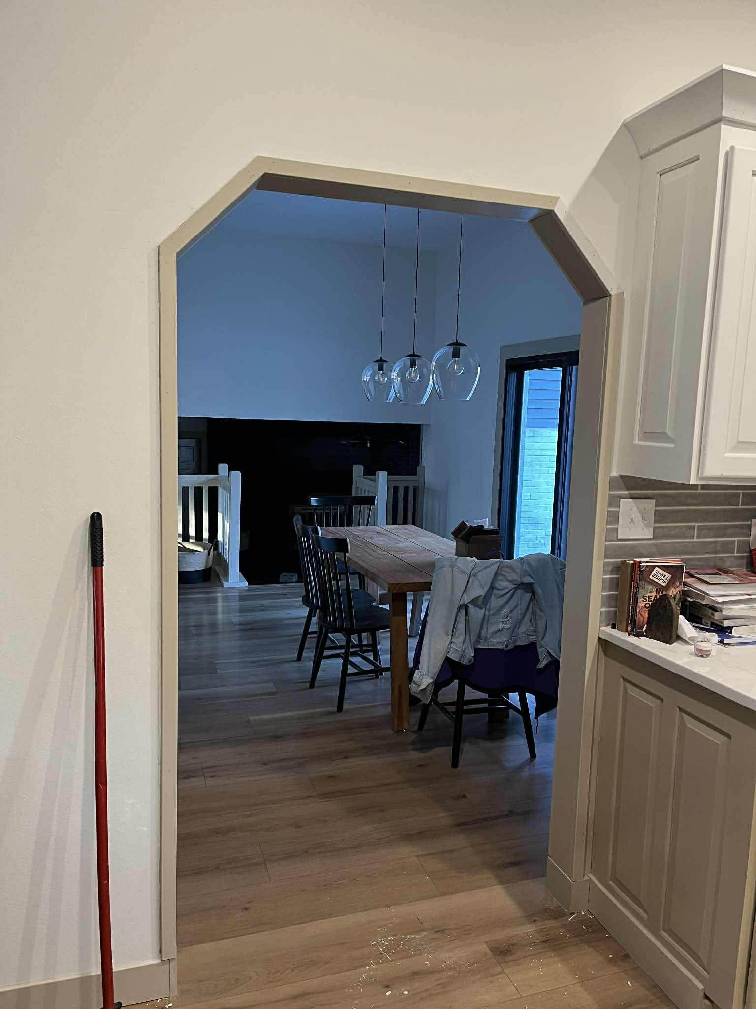 Custom archway from kitchen to dining room with hardwood floors and pendant lighting