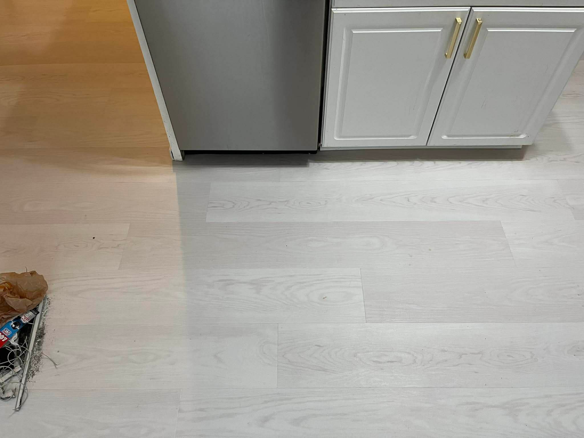 Kitchen flooring detail showing clean transition between white cabinets and light LVP flooring